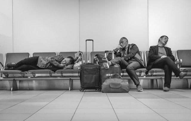 Ľudia spiaci na lavičkách na letisku
