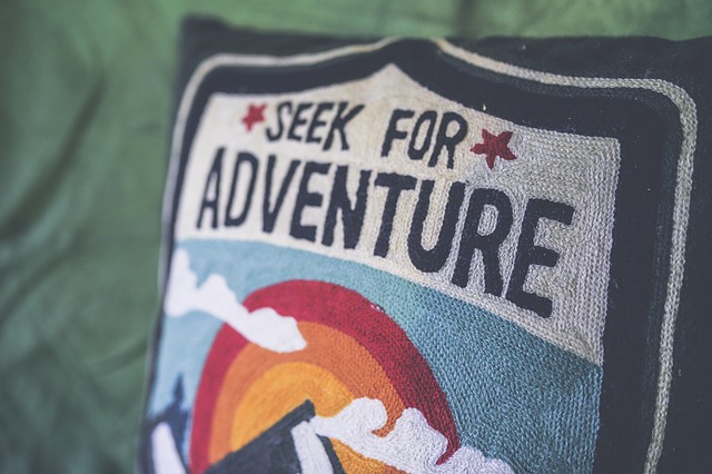 Vankúš s nápisom adventure položený na posteli.jpg